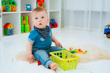 cute baby is sitting on the floor of the house, playing with colorful educational toys