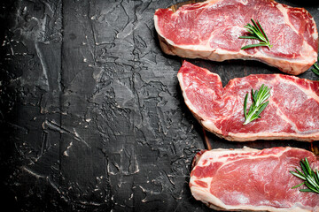 Raw beef steaks with fragrant rosemary.