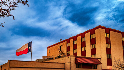 Lone Star Texas State Flag waving in the wind over town building in Odessa, Texas, USA, dramatic cloudscape