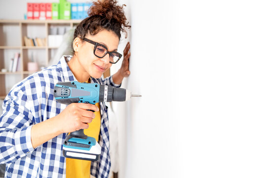 Woman doing home improvement using electric screwdriver