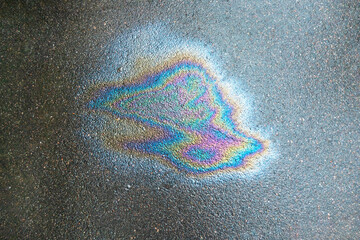 Iridescent spot of gasoline. Petrol on the asphalt a big polluted puddle water. A rainbow slick of gasoline