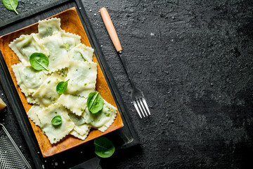 Ravioli with spinach leaves on the cutting Board.
