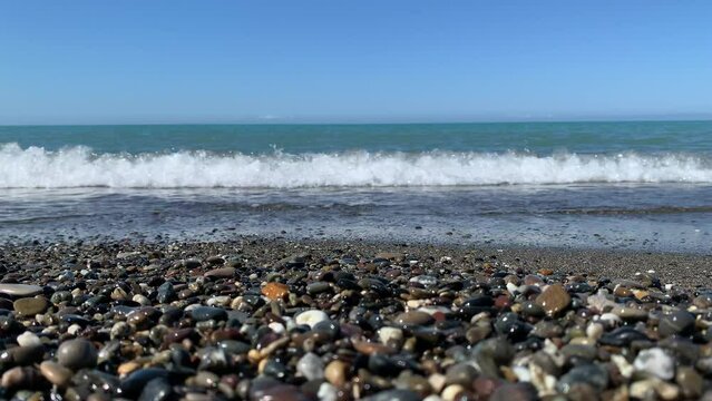 The calm sea floods the sea pebbles on the shore