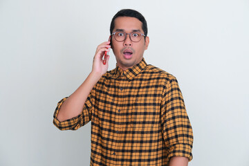 Adult Asian man showing shocked expression when answering a phone call