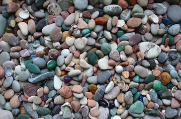 Small smooth pebbles, translucent colored minerals and seashells texture background
