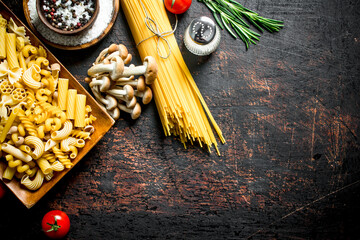 Different types of raw pasta with tomatoes, spices and mushrooms.