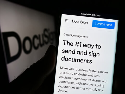 Stuttgart, Germany - 01-13-2023: Person holding smartphone with webpage of US electronic signature company DocuSign Inc. on screen with logo. Focus on center of phone display.