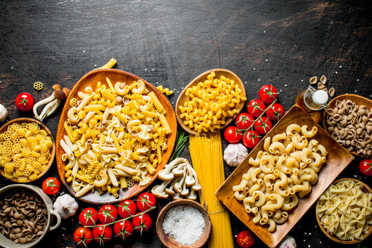 Assortment of different types of raw pasta with mushrooms, tomatoes and garlic.