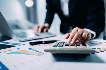 Businesswomen or Accountants use a calculator to work with financial statements and analyze company financial reports. investment, balance sheets, taxes, planning and business strategies concept.