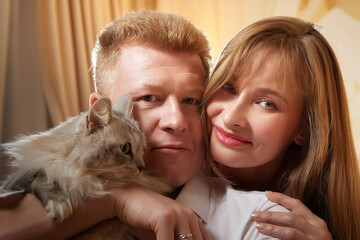 Happy loving couple with a big fat fluffy cat in the room