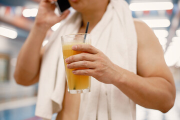 Cropped photo of a man standing in swimming pool holding a glass with juice