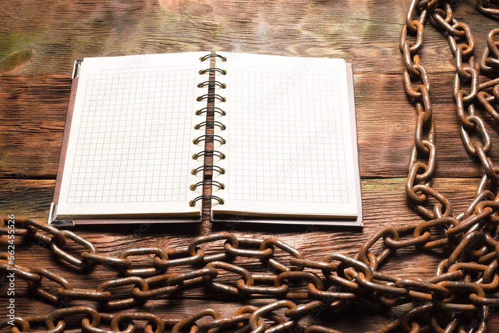 Wall mural open blank page notebook with copy space and old rusty iron chain on the wooden table background. to