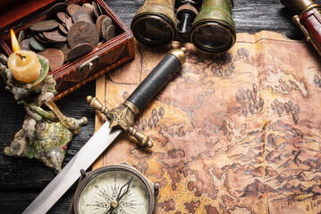 Ancient pirate treasure map, compass, chest with ancient coins and musket gun on the table top view...