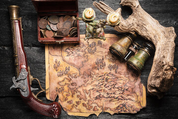 Ancient pirate treasure map, chest with ancient coins and musket gun on the table top view concept...