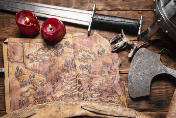 Treasure map of ancient lands. Ancient journey concept. Old map and battle axe on the wooden flat lay table background.