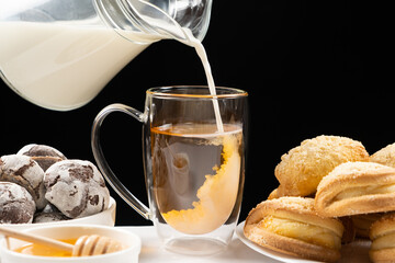 Making milk tea - milk from a glass jug is poured into black English tea.
