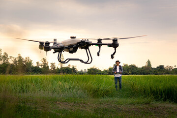Fototapeta na wymiar Agricultural specialist controls agriculture drone with remote controller for spraying fertilizer and pesticide at rice field. Agriculture 5g, Smart farming, Smart technology concept.
