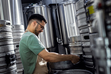 Fototapeta na wymiar Man working in craft brewery examining production of the beer.