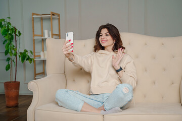 Closeup image of a beautiful woman waving hands while using mobile phone for video call at home