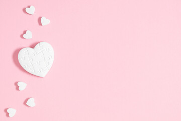 Valentine's Day background. White cute hearts confetti scattered on isolated pastel pink background. Valentine's day concept. Flat lay, top view, copy space