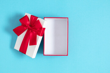 Open red gift box with red bow on isolated pastel blue background. Valentine's day concept....