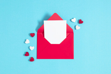 Valentine's Day concept. Red heart shaped confetti envelope on  isolated blue background. Flat lay,...