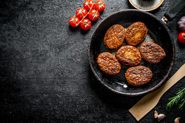 Cutlets in the pan with a wooden spatula and cherry.