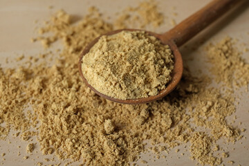 Spoon with aromatic mustard powder on wooden table, closeup
