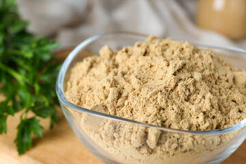 Bowl of aromatic mustard powder on table, closeup