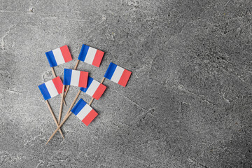 Fototapeta na wymiar Small paper flags of France on grey table, flat lay. Space for text