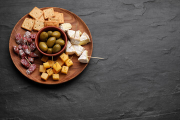 Toothpick appetizers. Pieces of cheese, sausage and olives on black table, top view with space for text