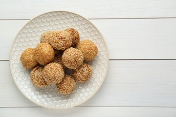 Delicious sesame balls on white wooden table, top view. Space for text