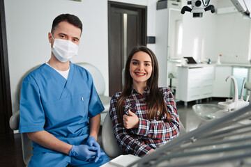 Fototapeta na wymiar Closeup portrait happy health care professional dentist, satisfied smiling woman patient in office giving thumbs up sign gesture. Successful treatment procedure, care, outcome. Positive emotion