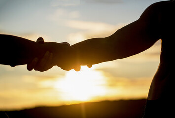 Two hands silhouette on sky background, connection or help concept. Outstretched hands, salvation,...