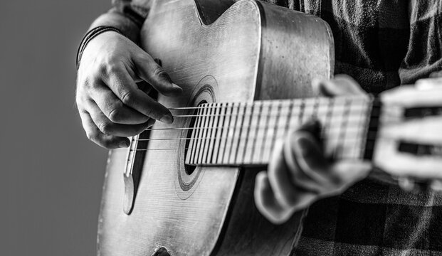 Close up hand playing guitar. Guitars acoustic. Male musician playing guitar, music instrument. Man's hands playing acoustic guitar, close up. Acoustic guitars playing. Black and white