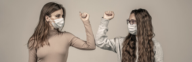 Elbow bump. Friends in protective medical mask on his face greet their elbows in a quarantine. Friends bump elbows. Coronavirus epidemic