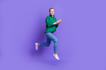 Fototapeta na wymiar Full length profile portrait of carefree crazy person jump rush hurry use telephone isolated on purple color background