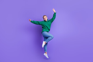 Fototapeta na wymiar Full length photo of excited dreamy lady wear green sweater rising hands arms jumping high isolated violet color background