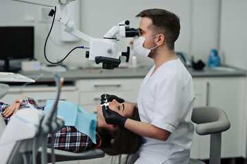 Examining thoroughly. Upbeat male dentist using a professional microscope and checking for cracks...