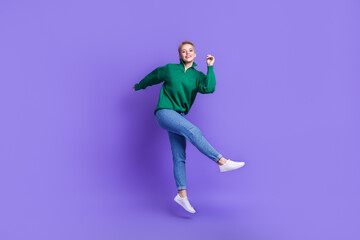 Fototapeta premium Full length photo of dreamy pretty lady wear green sweater having fun dancing jumping high isolated violet color background
