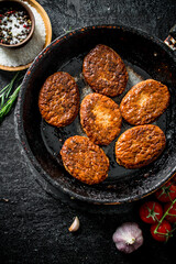Cutlets in pan with spices and tomatoes.