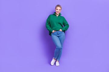 Fototapeta na wymiar Full length photo of pretty adorable lady wear green sweater hands arms pockets walking isolated violet color background