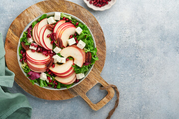 Salad. Fresh fruit green salad with feta cheese, apple, pomegranate, pecan and lettuce on white plate. Idea for healthy delicious winter Christmas salad. Healthy balanced eating. Top view.