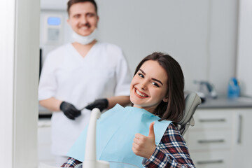 Obraz premium Happy young woman and male dentist after treatment in clinic