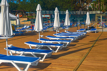 View of the pier with blue sun loungers and white umbrellas on the seashore in Kemer. Turkey