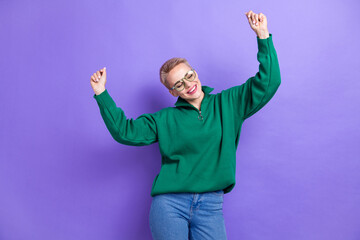 Photo of young careless funky lady wear stylish outfit green zip jacket hands up listen rhythm vibe music relax isolated on violet color background