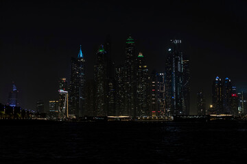 Fototapeta na wymiar Beautiful night view of Dubai skyscrapers from the sea. skyline of Dubai Marina after sunset with a sea in the foreground