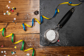 carnival confetti on wood background with slate and powdered sugar