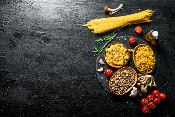 Different kinds of raw paste in bowls with tomatoes, garlic and mushrooms.