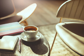In cafe morning, coffee cup and smart phone, tablet computer and note book on table with sunlight shines in the morning people relax in cafe with coffee drink before work, vintage tone